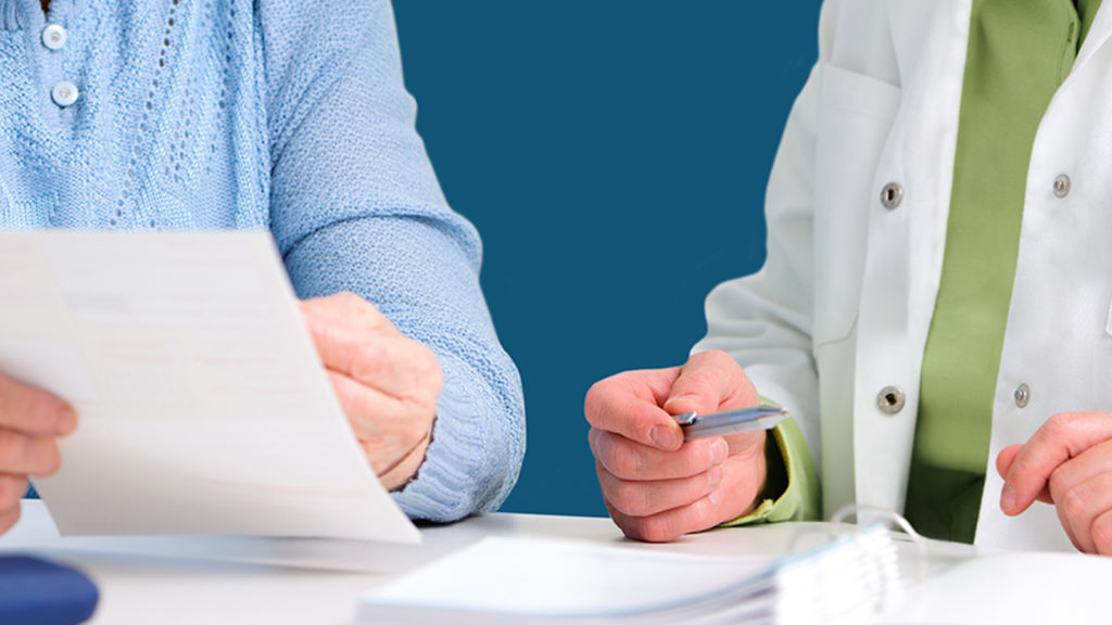 A close-up image of a doctor and patient discussing over a piece of paper