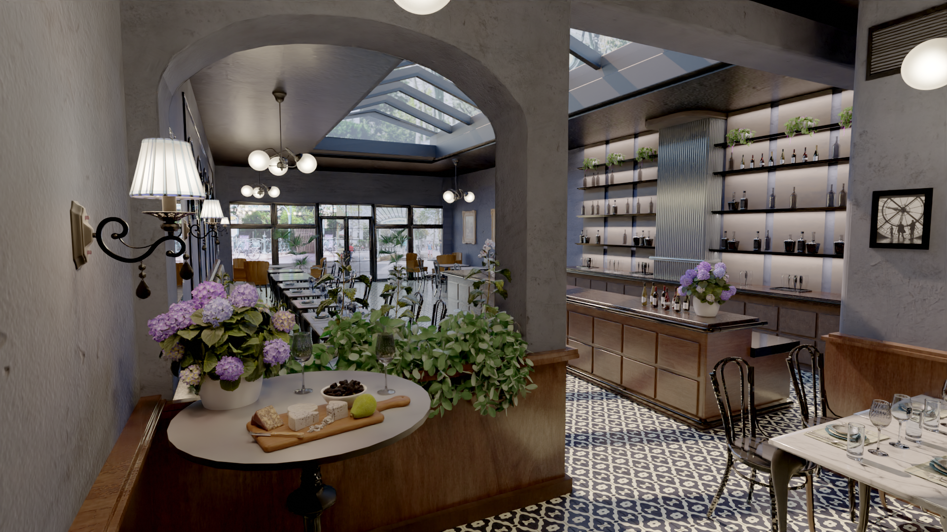 A cozy restaurant interior featuring vintage decor. The dining area has patterned tile flooring, tables with white tablecloths, and a wall of shelves with plants and bottles. A small table holds flowers, bread, cheese, and fruit. Large windows allow natural light in.