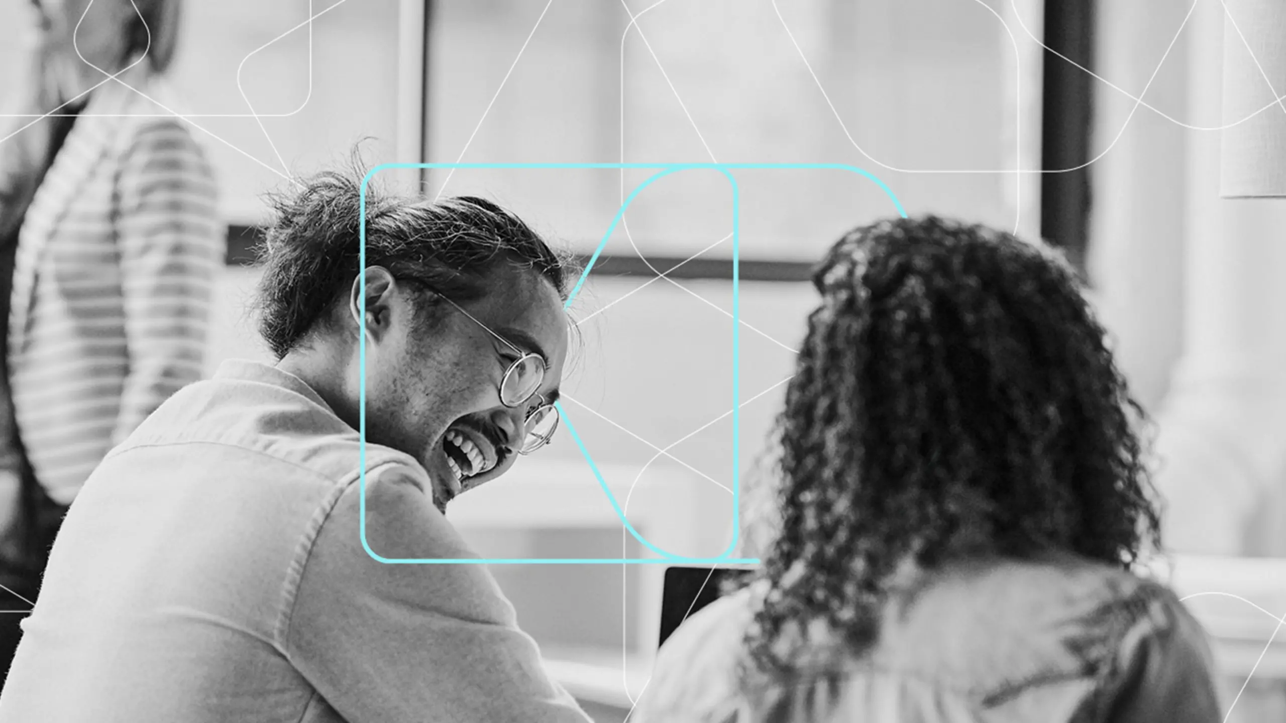 A black-and-white image of two people sitting at a table, focused on a screen. The person on the left has glasses and tied-back hair, while the other has curly hair. Abstract lines and shapes are overlaid on the image, adding a modern, tech-inspired design.
