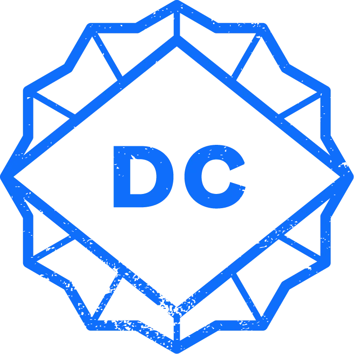 A blue geometric badge with a diamond shape in the center containing the bold letters "DC," surrounded by a starburst-style border.