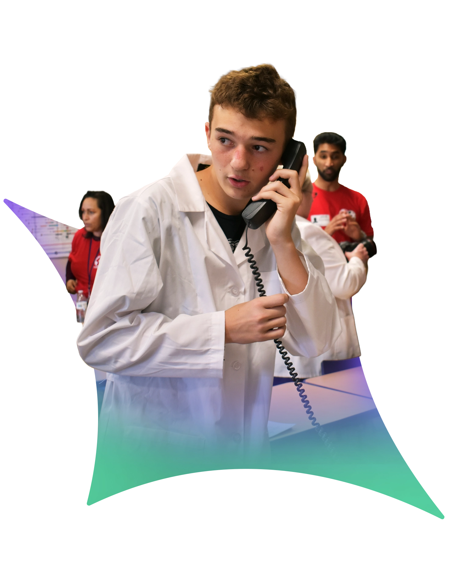 A young person in a white lab coat talks on a corded phone, looking to the side. Several people are in the background, some wearing red shirts, in what appears to be a busy experiential event or global awareness campaign.